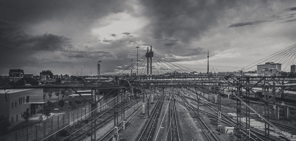 Bridge over railroad tracks against sky in city