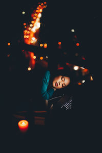 High angle view of young woman sleeping by window in darkroom at home