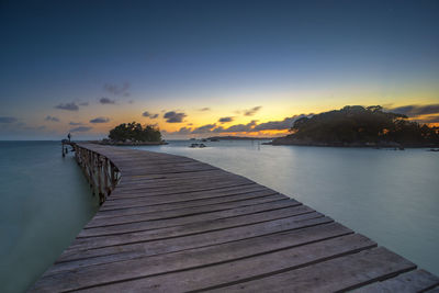Pier over sea against sky during sunset