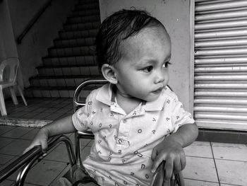 Cute boy looking away while sitting on floor