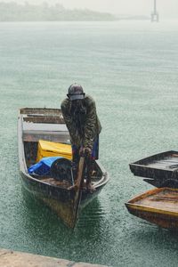 Mid adult man standing on boat in sea during rainfall