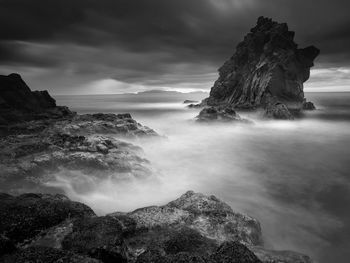 Rock formations in sea against cloudy sky at madeira