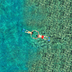 High angle view of couple holding hands and floating on sea