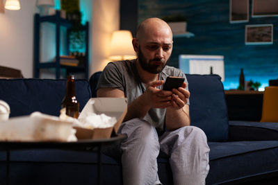 Man using mobile phone while sitting on sofa