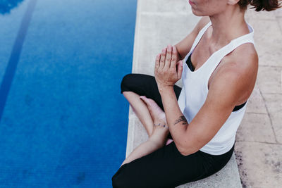 Low section of woman exercising by swimming pool