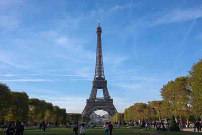 People at champ de mars by eiffel tower against sky