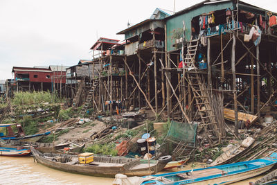 Fishing boats moored at harbor against abandoned houses