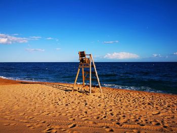 Lifeguard hut on beach against blue sky