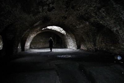 Rear view of silhouette man standing in tunnel