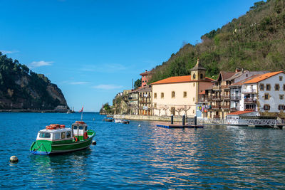 Boat in sea by buildings against sky