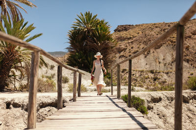 Woman walking by palm trees against sky