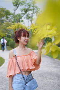 Young woman standing against plants