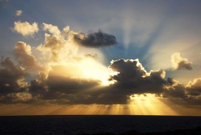 Scenic view of sea against cloudy sky during sunset