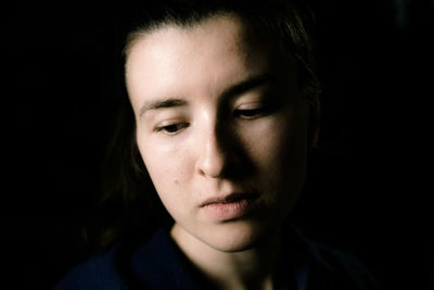 Close-up of woman looking down against black background