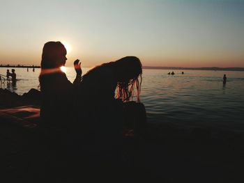 Friends sitting on pier during sunset