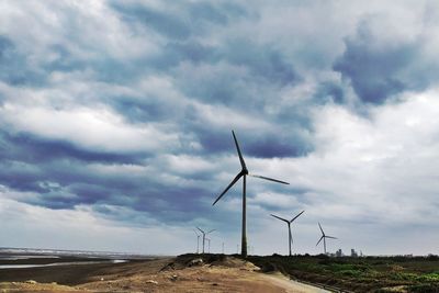 Windmills on field against sky