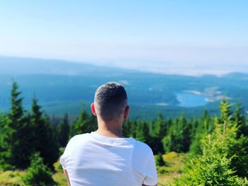 Rear view of man by trees against mountains and sky