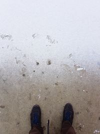 Low section of person standing on snowy land