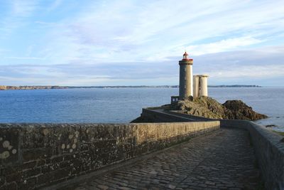 Lighthouse by sea against sky
