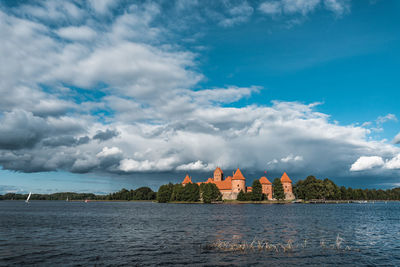 Trakai historical castle by lake against cloudy sky