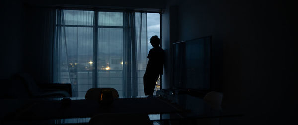 Side view of silhouette man standing by window at home