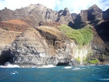 Scenic view of rocks in sea against mountains napali coast