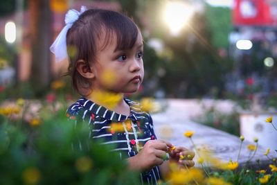 Portrait of cute girl looking away at flower