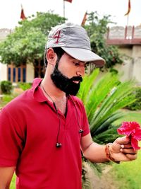 Midsection of man standing on red flowering plant