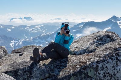 Man photographing while sitting on mountain