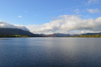 Scenic view of lake with mountain range against cloudy sky