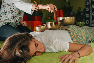 Midsection of therapist playing rin gong on young woman at spa