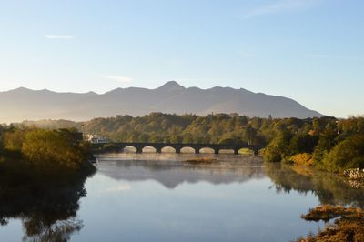 Scenic view of river by bridge against sky