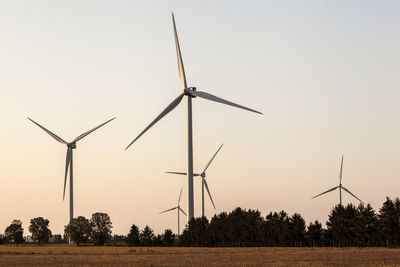 Windmill on field against sky during sunset