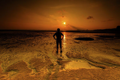 Silhouette man standing on beach against sky during sunset