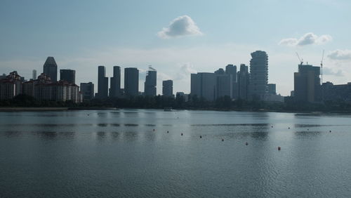 Sea and buildings in city against sky