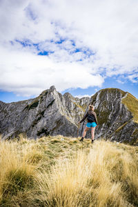 Rear view of man walking on mountain against sky