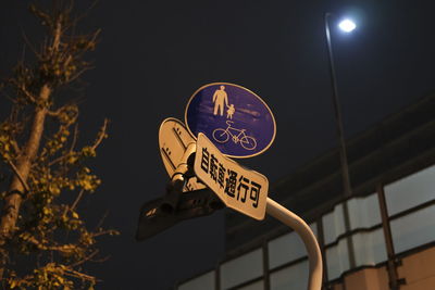 Low angle view of road sign against sky at night