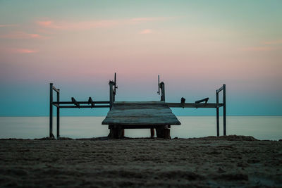 Lifeguard hut on beach against sky during sunset