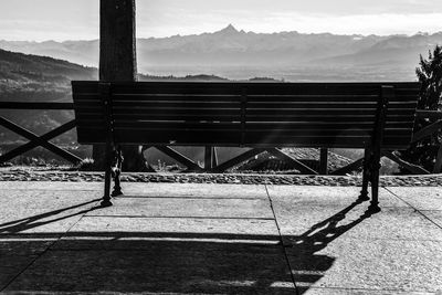 Empty bench on table against mountain range
