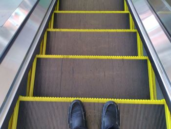 Low section of person standing on escalator