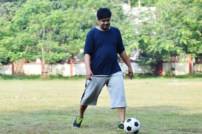 Rear view of man playing soccer at park