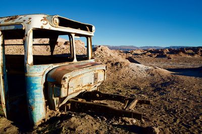 Abandoned truck on landscape against clear blue sky