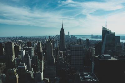 Aerial view of buildings in city against cloudy sky