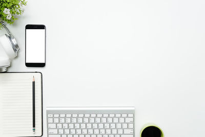 Directly above shot of technologies with book on white background