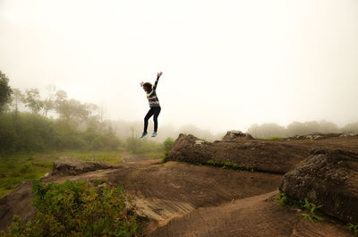 Man jumping on mountain against sky