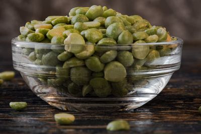 Close-up of green split peas in bowl on wooden table