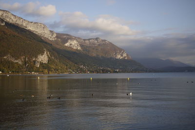 Scenic view of sea by mountains against sky