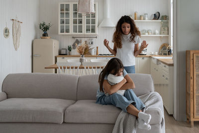 Full length of young woman sitting on sofa at home