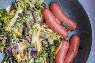 Fried sausages and vegetables with mushrooms and chicken egg on skillet