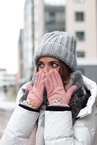 Portrait of woman wearing hat in city during winter